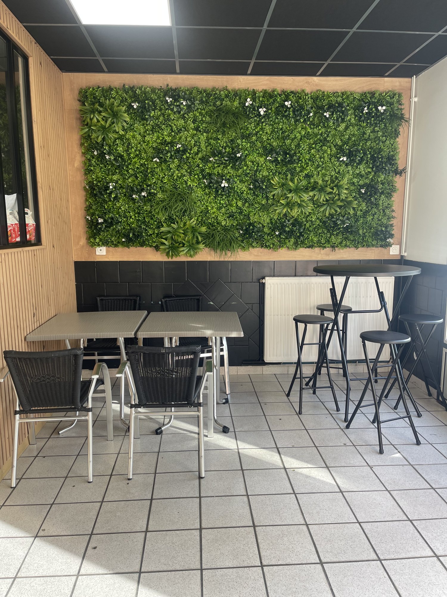 Le coin tables hautes et son mur végétal